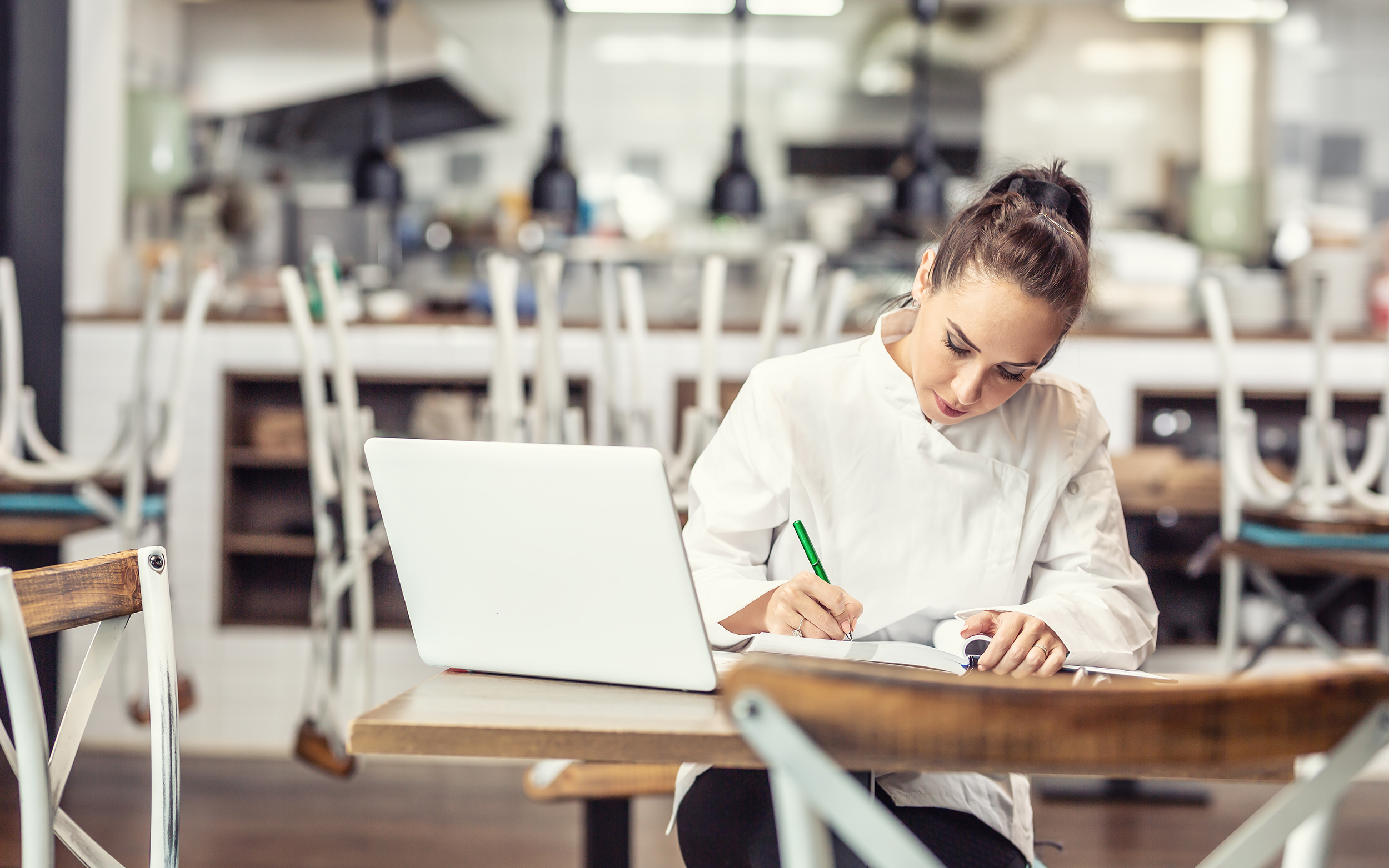 Chef cuisinier dans sa cuisine qui prend des notes